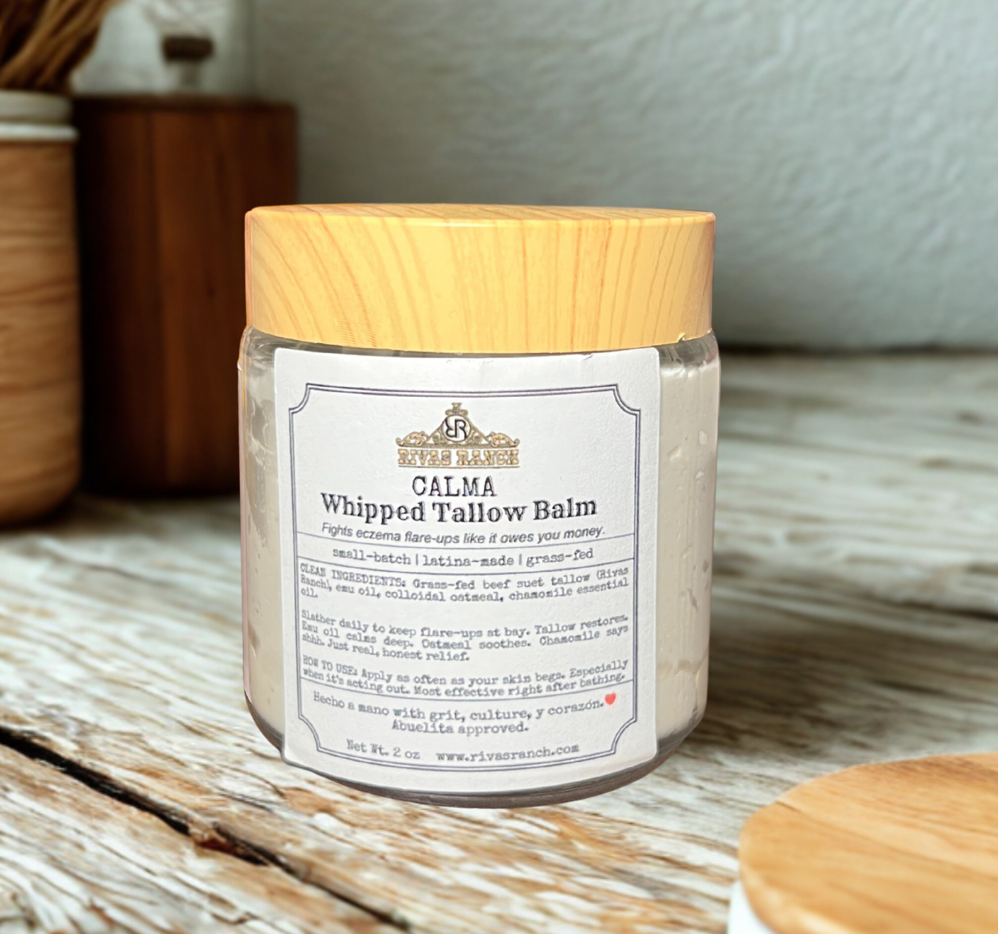 Jar of Calma Whipped Tallow Balm with wooden lid on a wooden surface