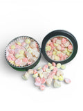 Two small round containers with colorful candy hearts on a white background