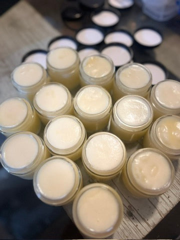 Multiple small jars with a white cream-like substance on a wooden surface.